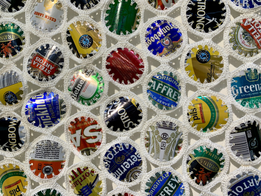 Art Textiles Made in Britain - circles of cut out beer cans crocheted together with white thread - called Keep the Homeless Warm